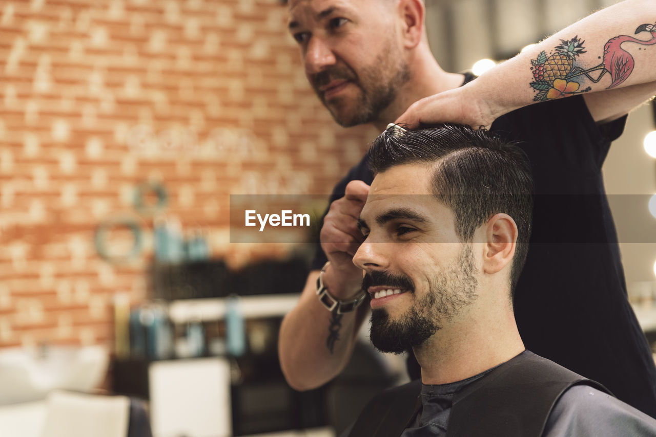 Midsection of barber cutting man hair in salon