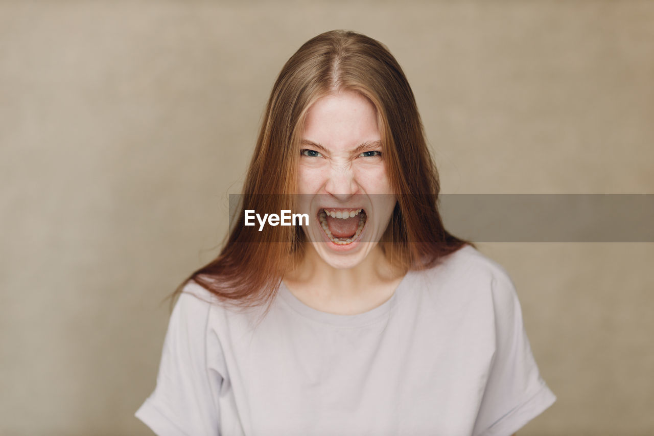 portrait of smiling young woman standing against wall
