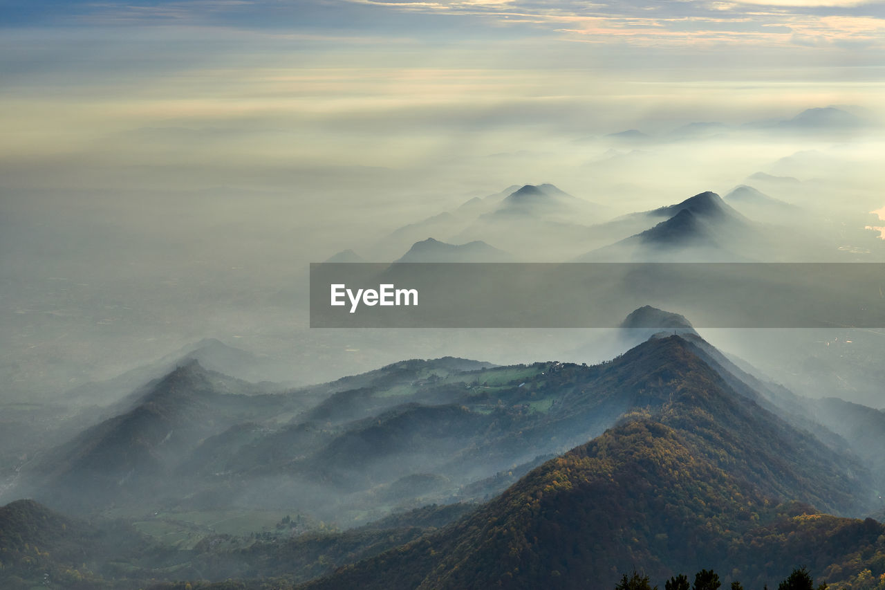 Scenic view of mountains with mist against sky 