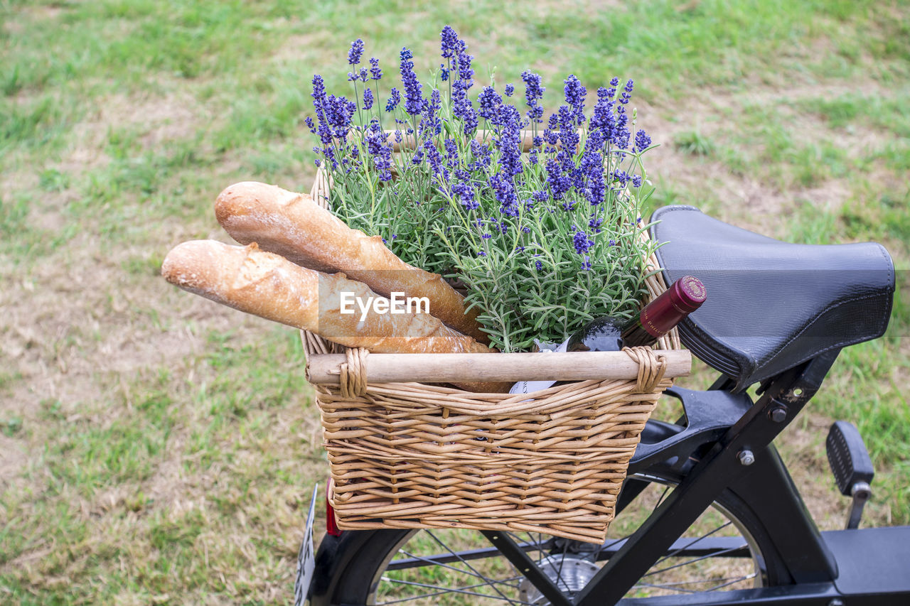 High angle view of bread with lavender flowers and wine bottle in bicycle basket