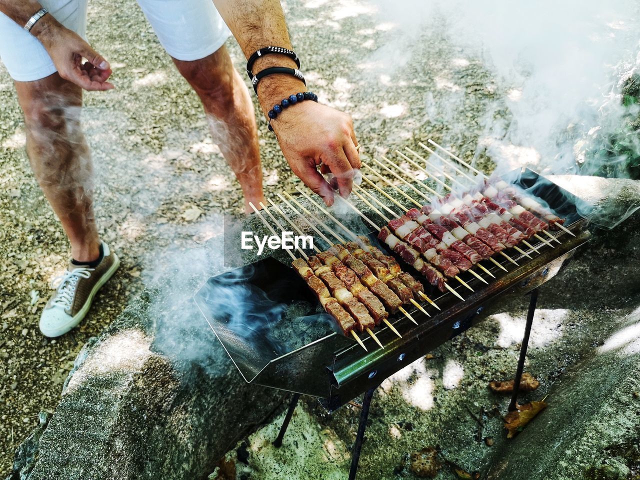 Boy grills skewers of meat outdoors during a picnic