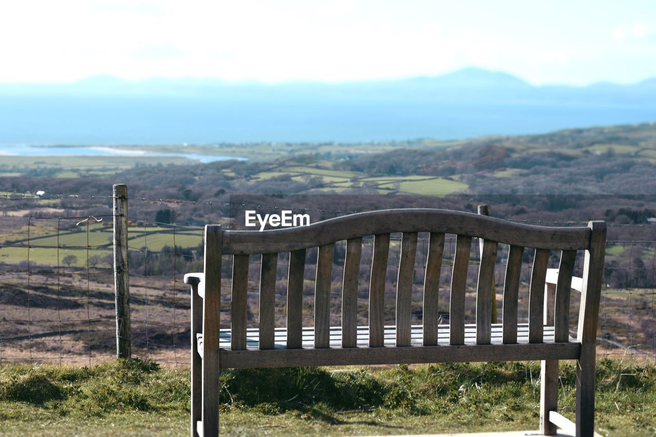 Empty bench over landscape against sky