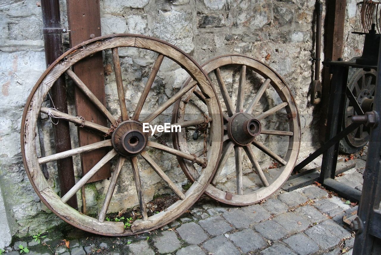 Wagon wheels on footpath against wall