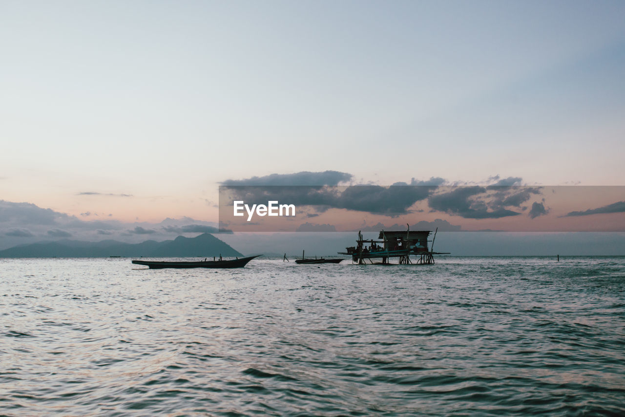 Silhouette boat in sea against sky during sunset