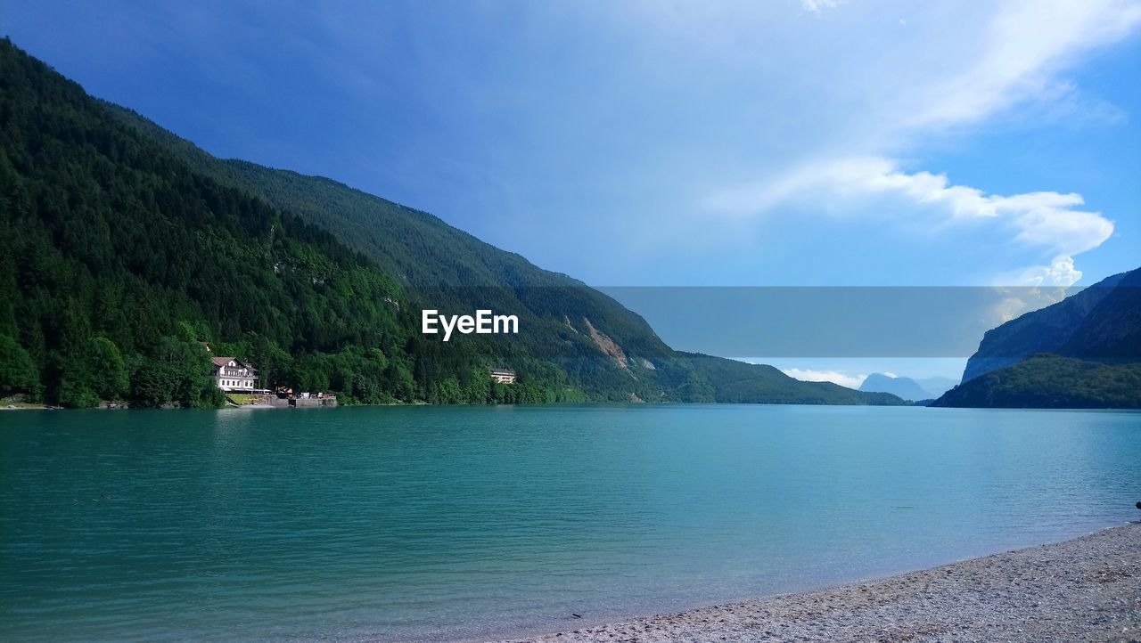 Scenic view of sea by mountains against sky