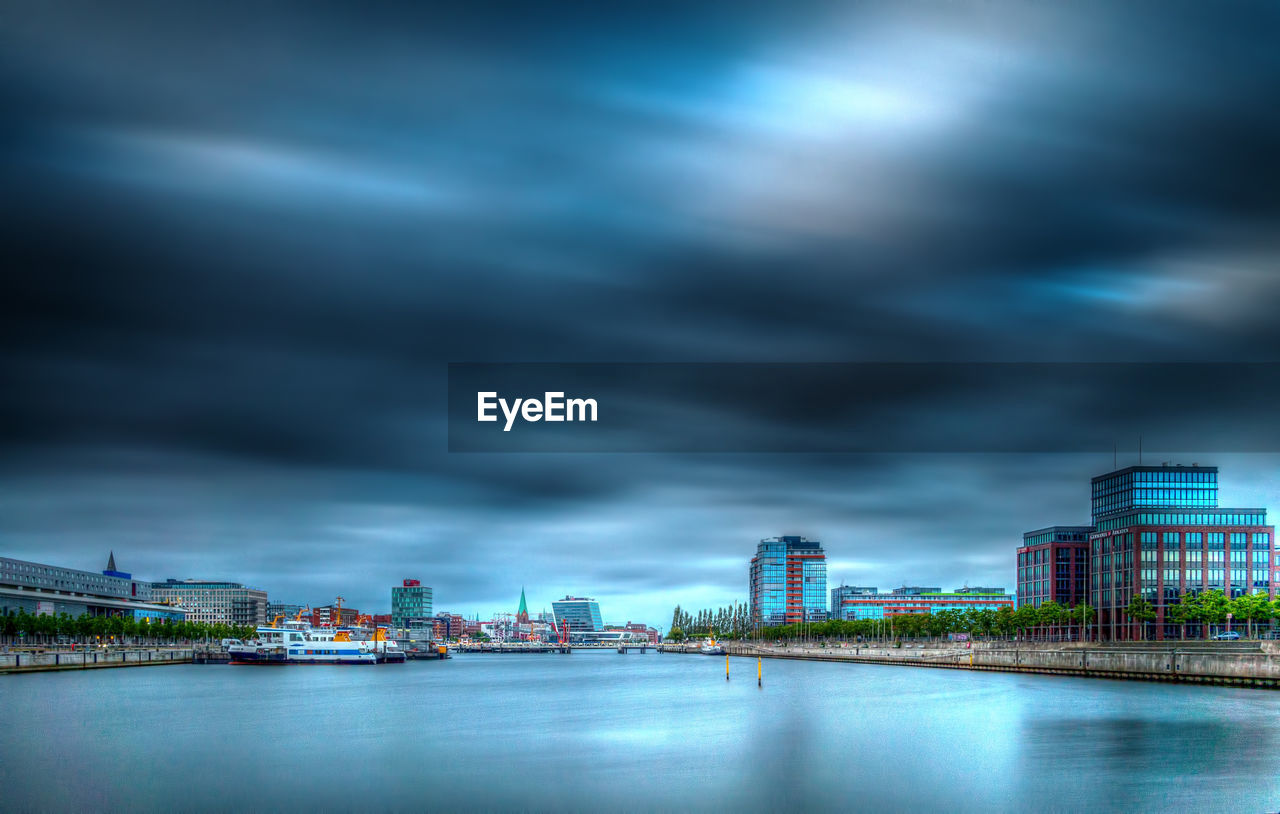 City with river against cloudy sky