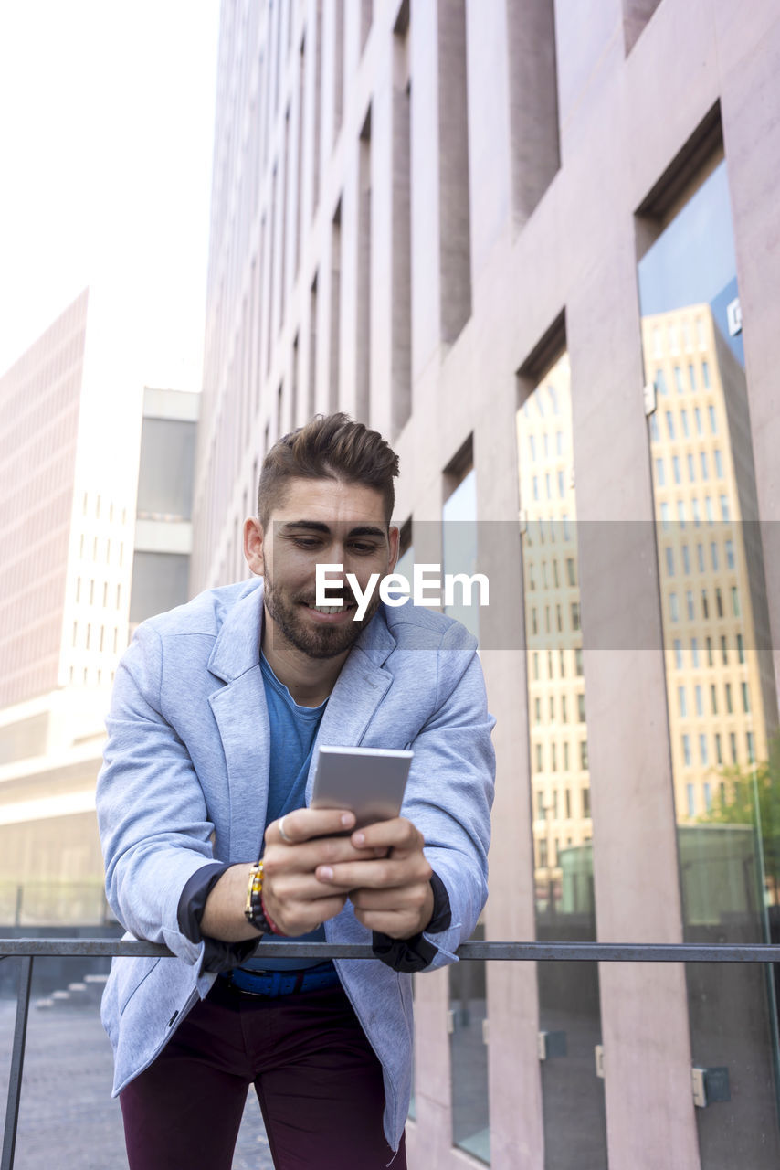 Smiling businessman using mobile phone outdoors