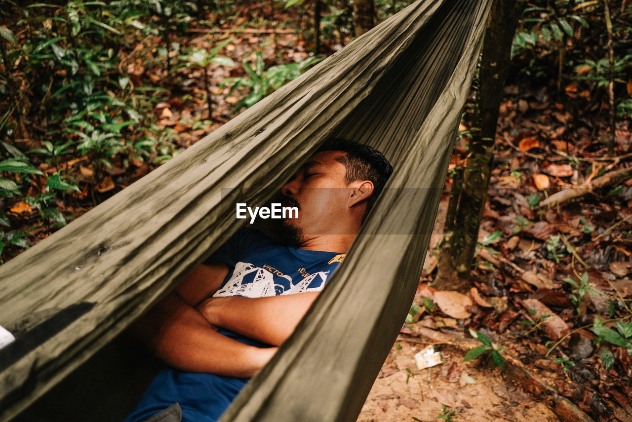Portrait of man relaxing on hammock in forest