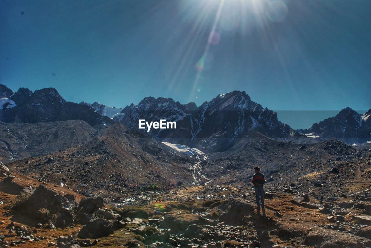 Man standing on land against sky during sunny day