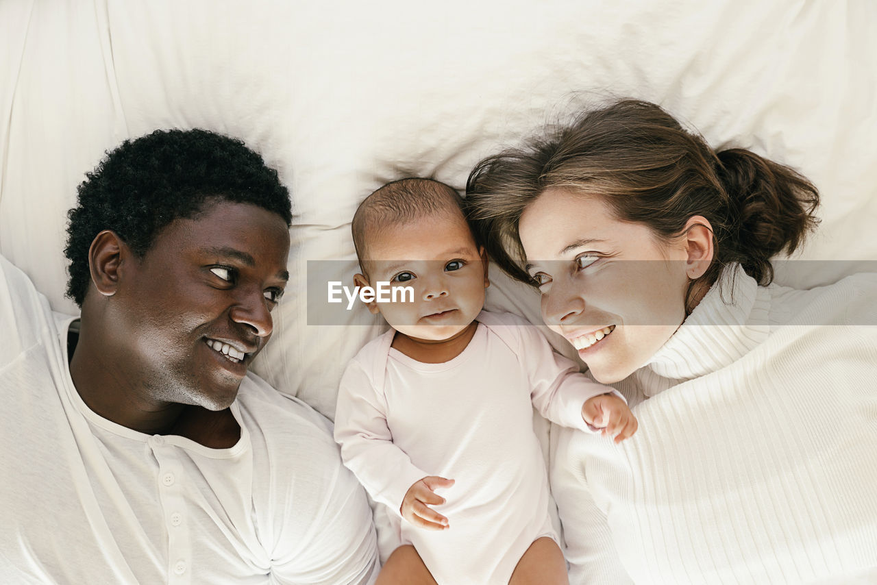 Parents with daughter lying on bed at home