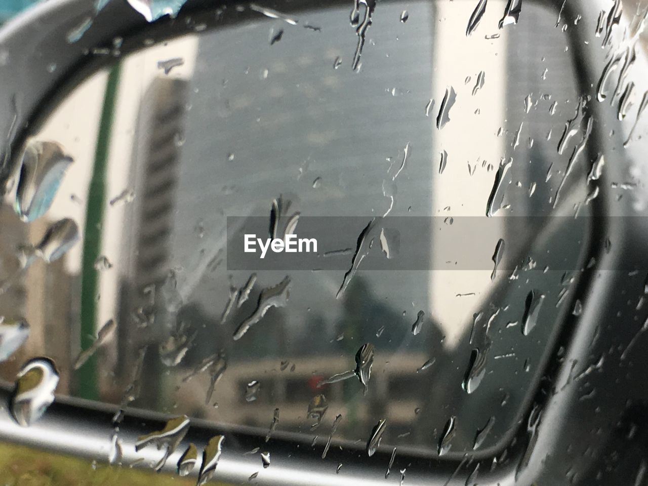 CLOSE-UP OF WET GLASS WINDOW AGAINST CAR