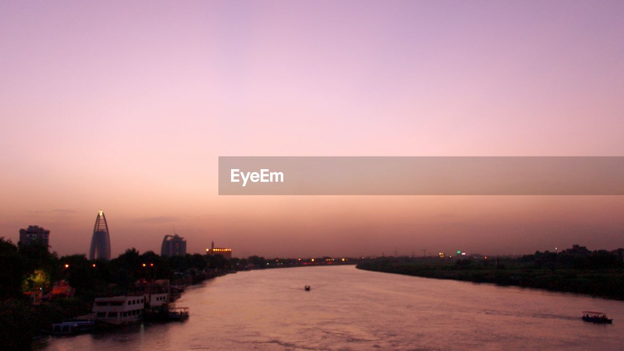 Scenic view of river and city against sky during sunset