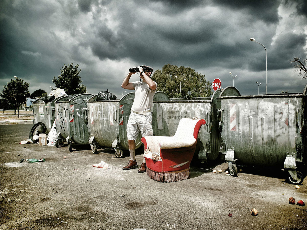 Man looking into binoculars by trashcans