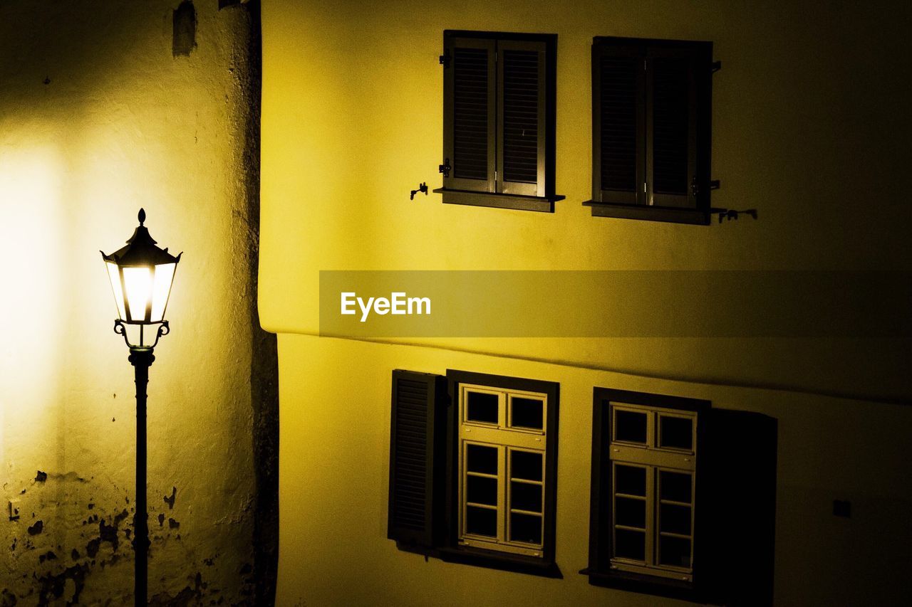 ILLUMINATED STREET LIGHT ON YELLOW WALL