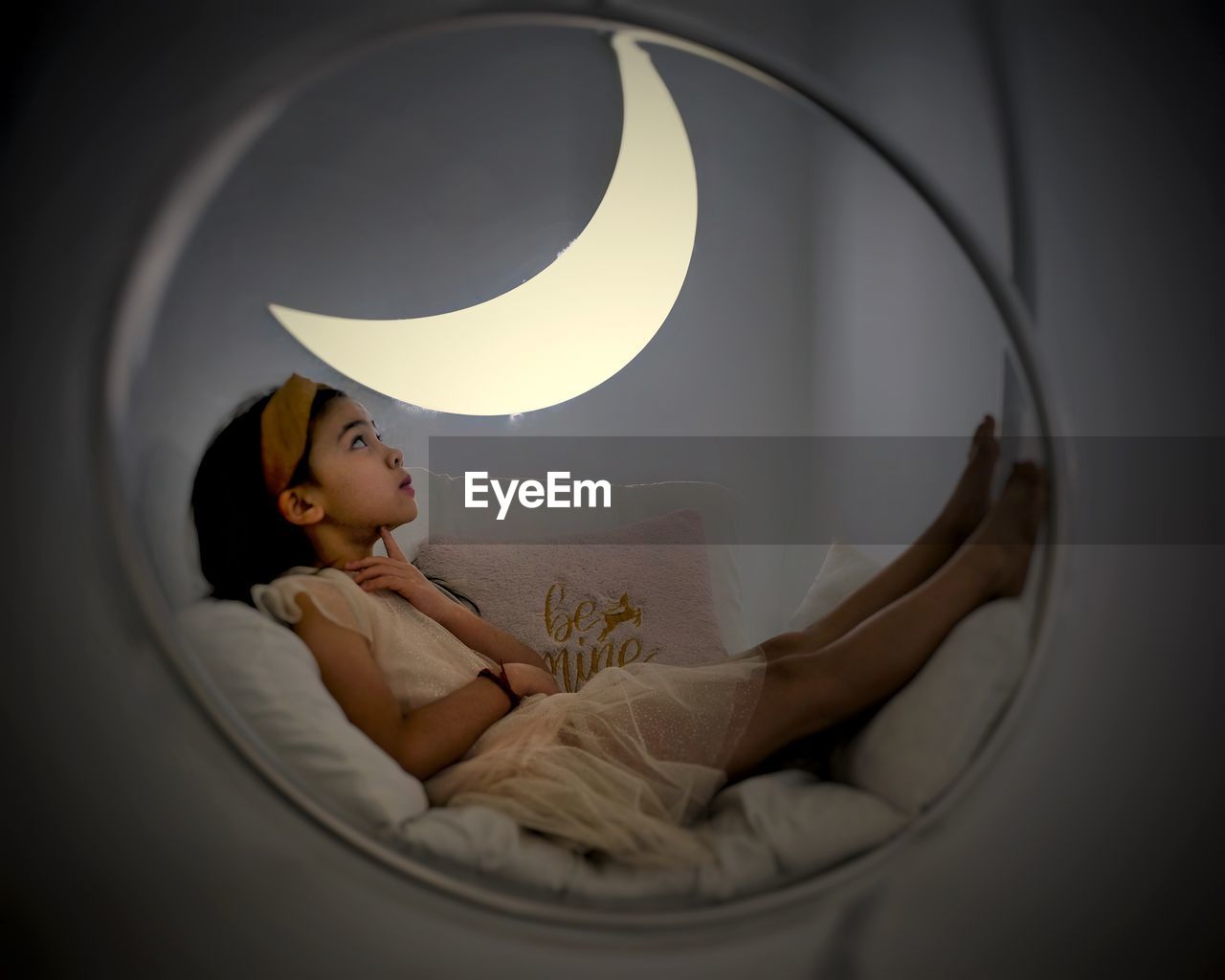 Girl looking at moon while lying on bed