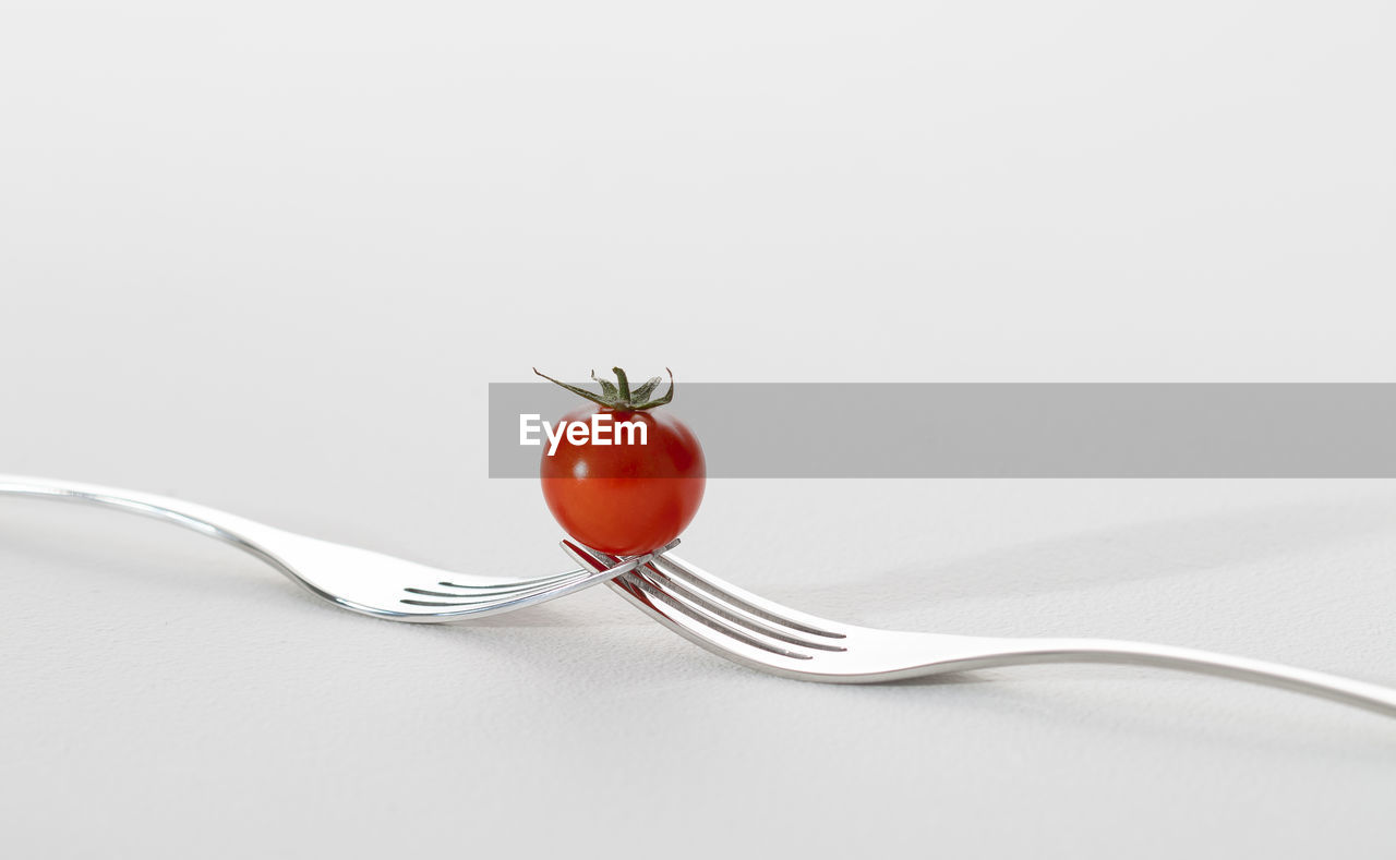 Close-up of red berries on table against white background