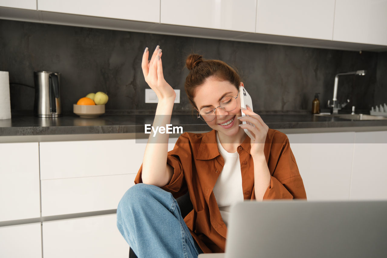 young woman using laptop while sitting on table