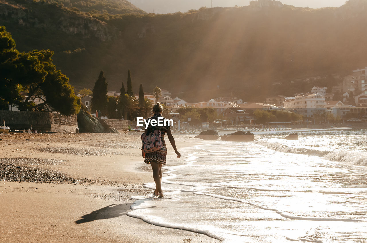 Rear view of woman walking at shore