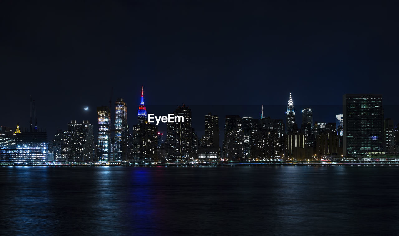 Illuminated cityscape at waterfront during night