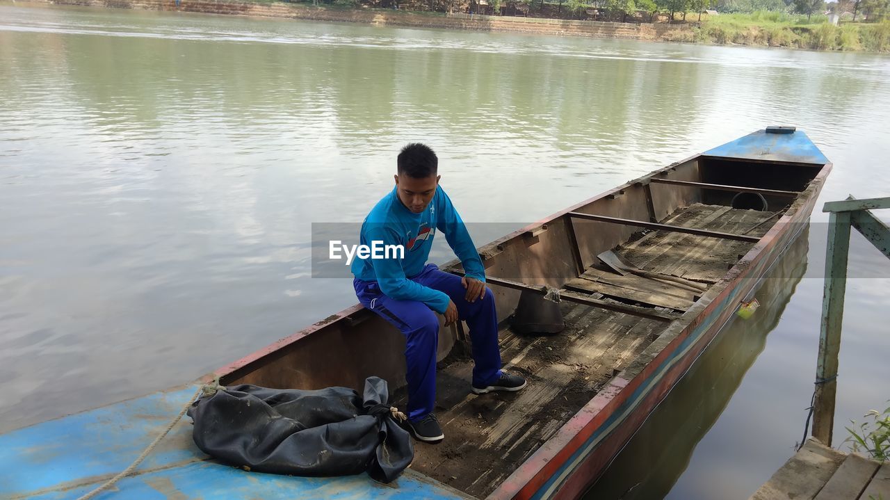 Rear view of man sitting on boat in lake