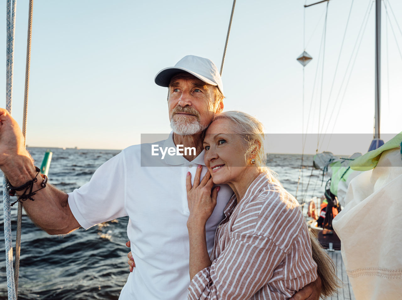 Smiling senior couple standing on boat during sunset