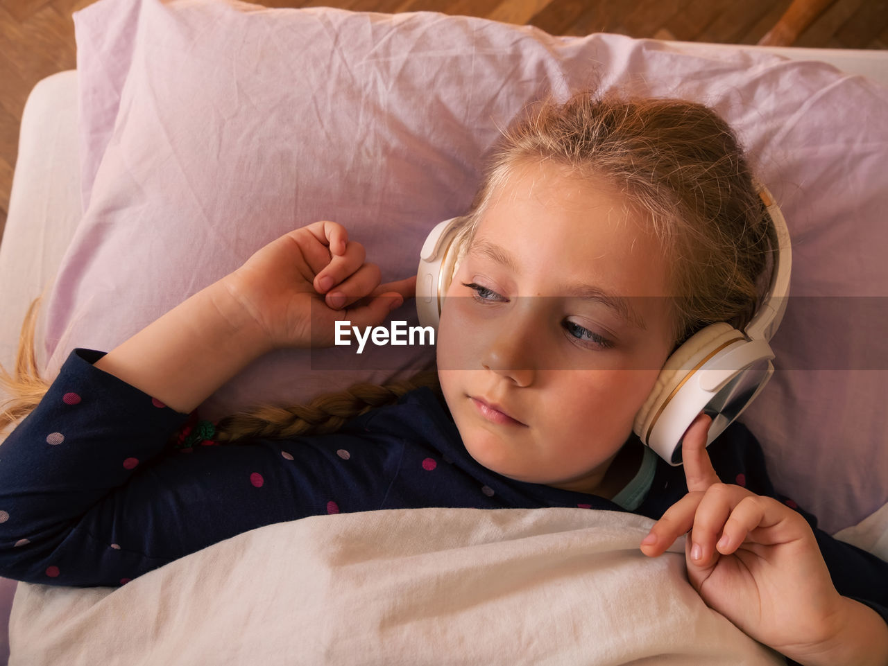 Child girl in headphones listens music for better sleep relaxing podcast stress relief in smartphone