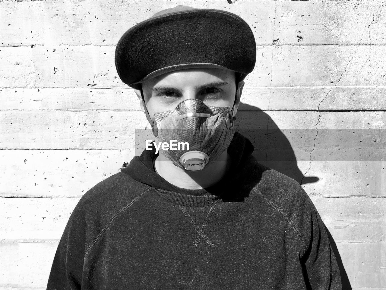 Portrait of man wearing mask standing against wall