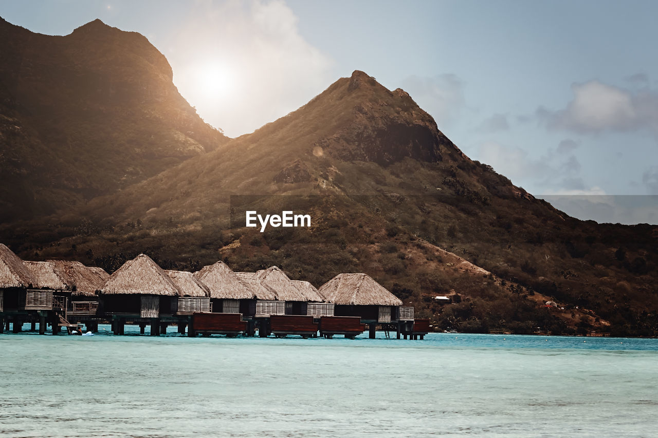 Bora bora huts in the ocean - mountains in the background - pacific ocean