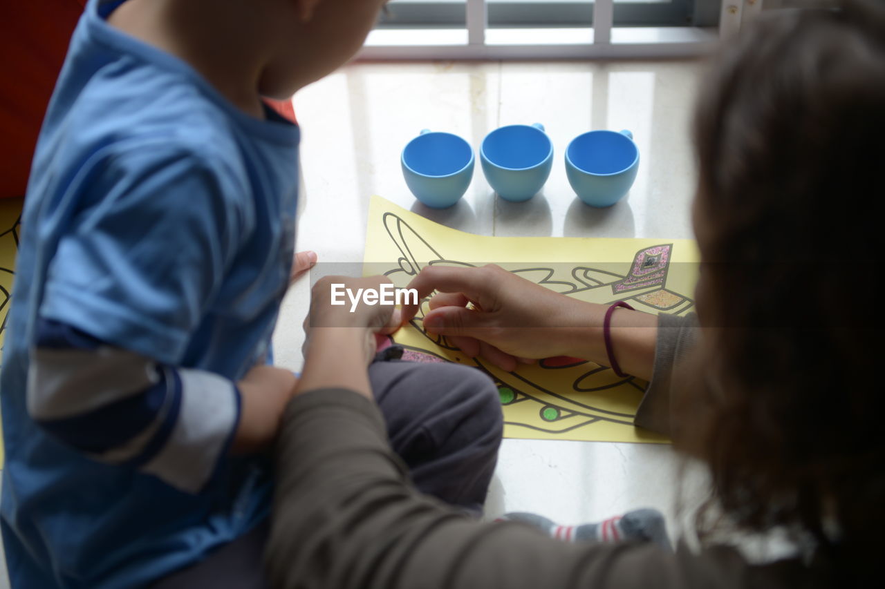 High angle view of mother and son coloring on table at home