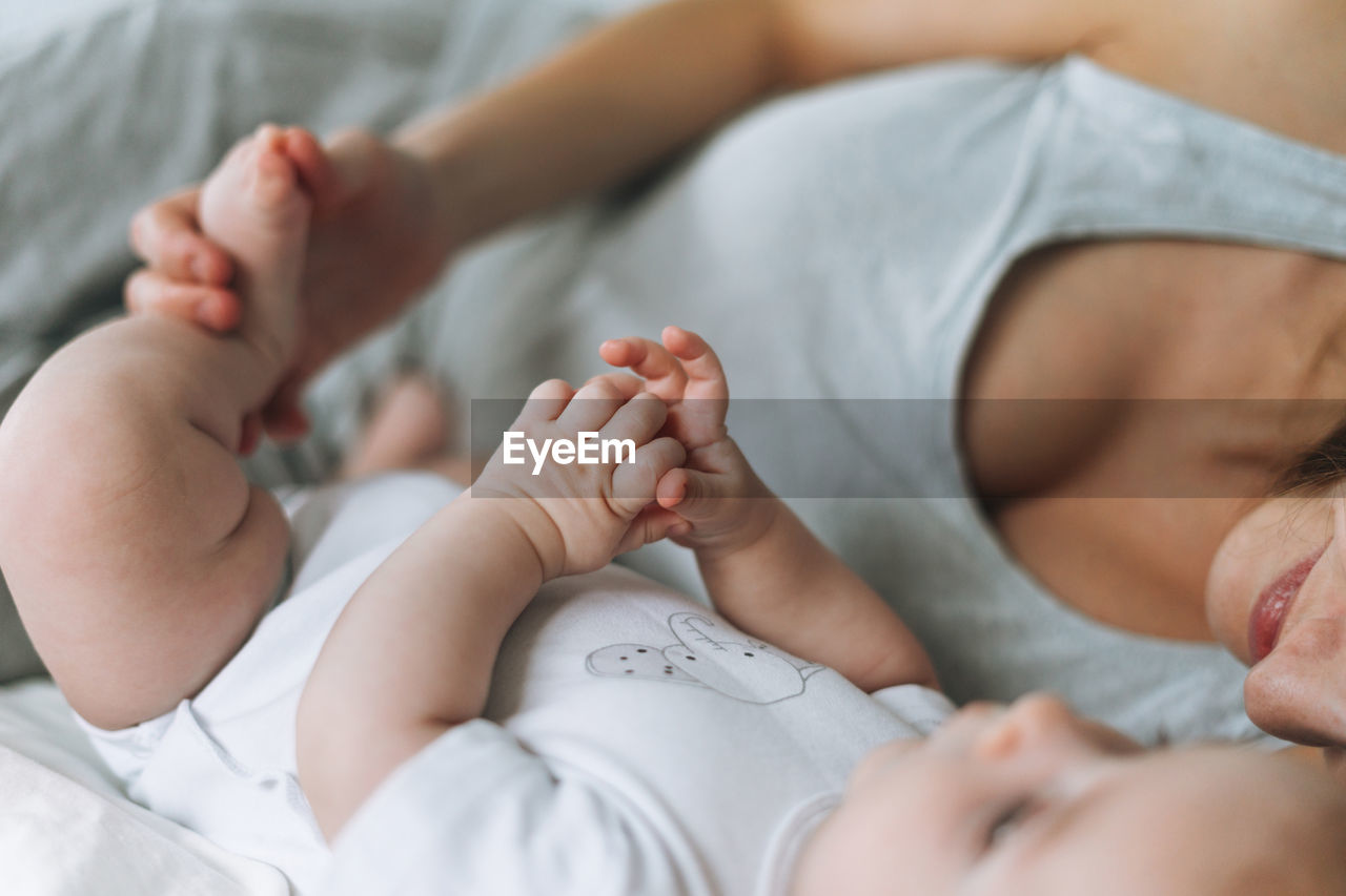 Young mother having fun with cute baby girl on bed, natural tones, love emotion