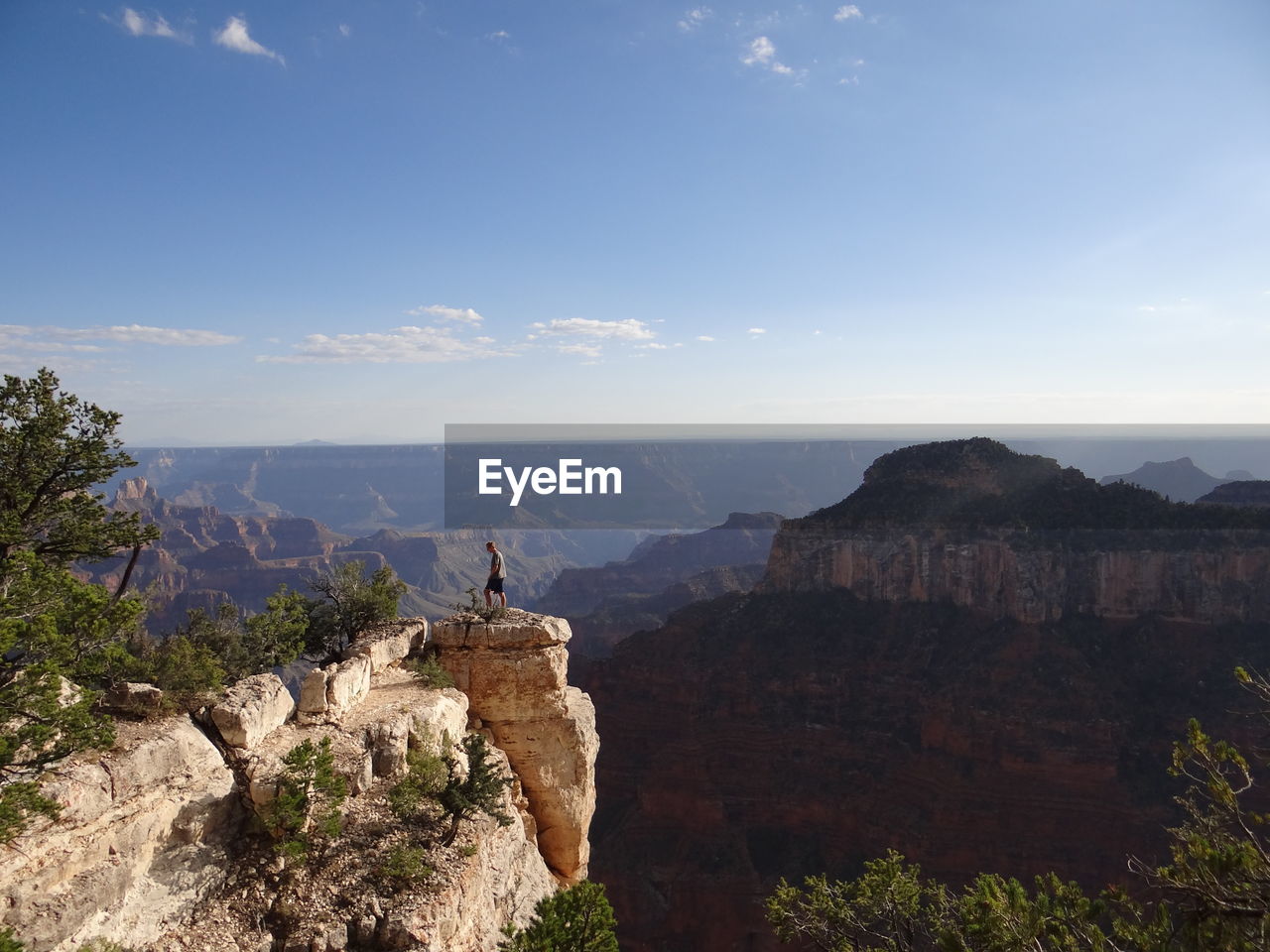 Rear view of man standing on rock while looking at mountains