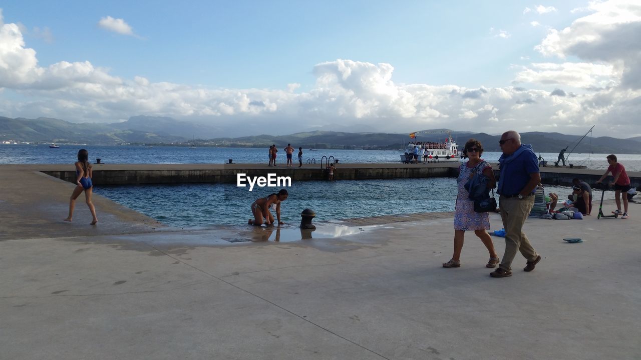 PEOPLE ENJOYING ON BEACH AGAINST SKY