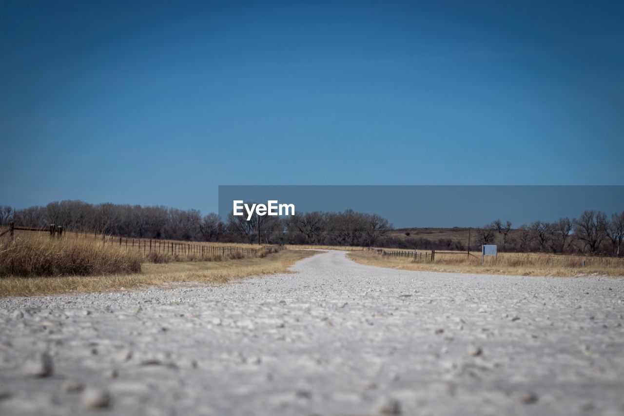 ROAD AMIDST FIELD AGAINST CLEAR SKY