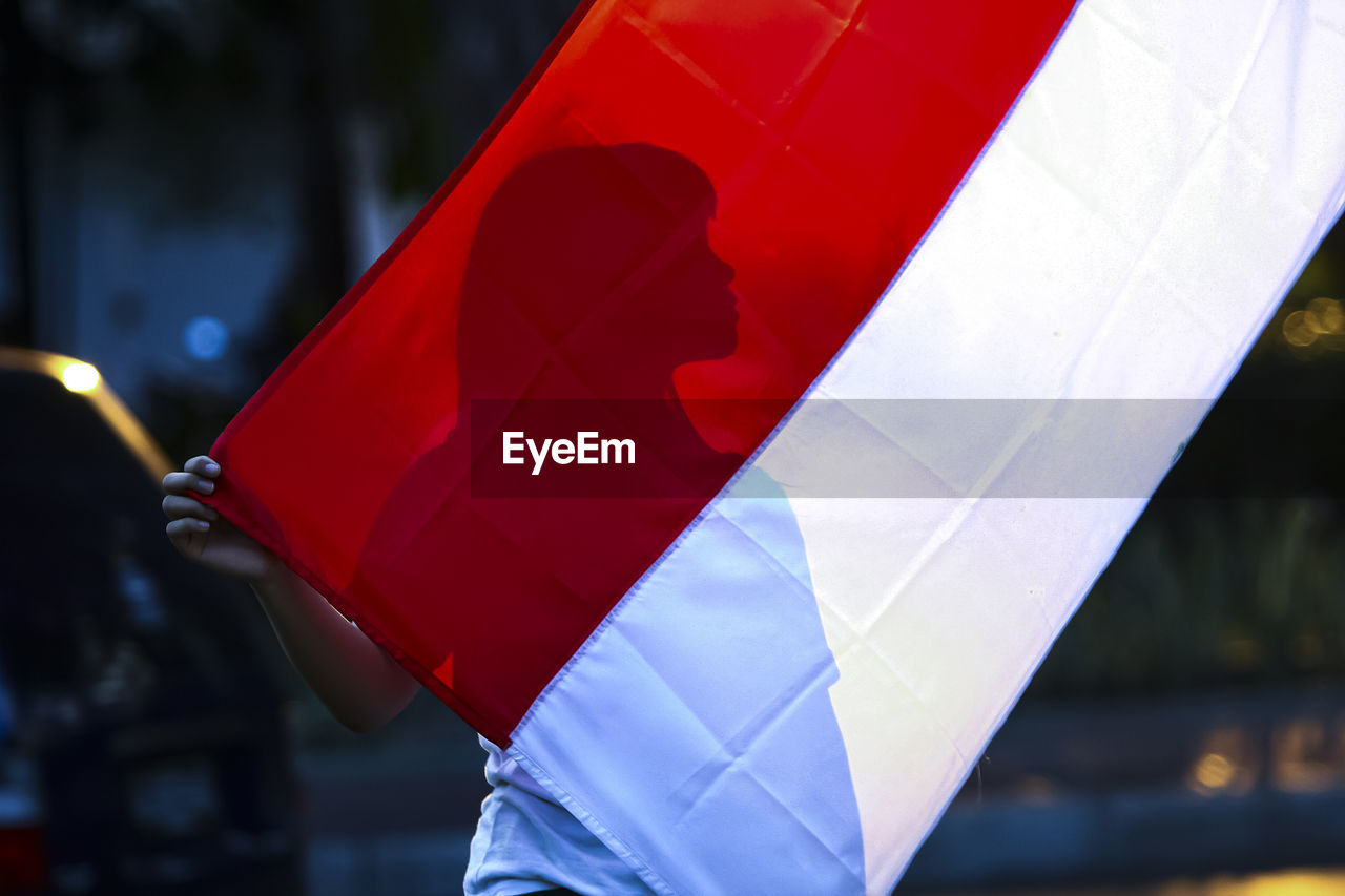 red, transportation, vehicle, focus on foreground, flag, outdoors, blue, day, city, mode of transportation, close-up, one person