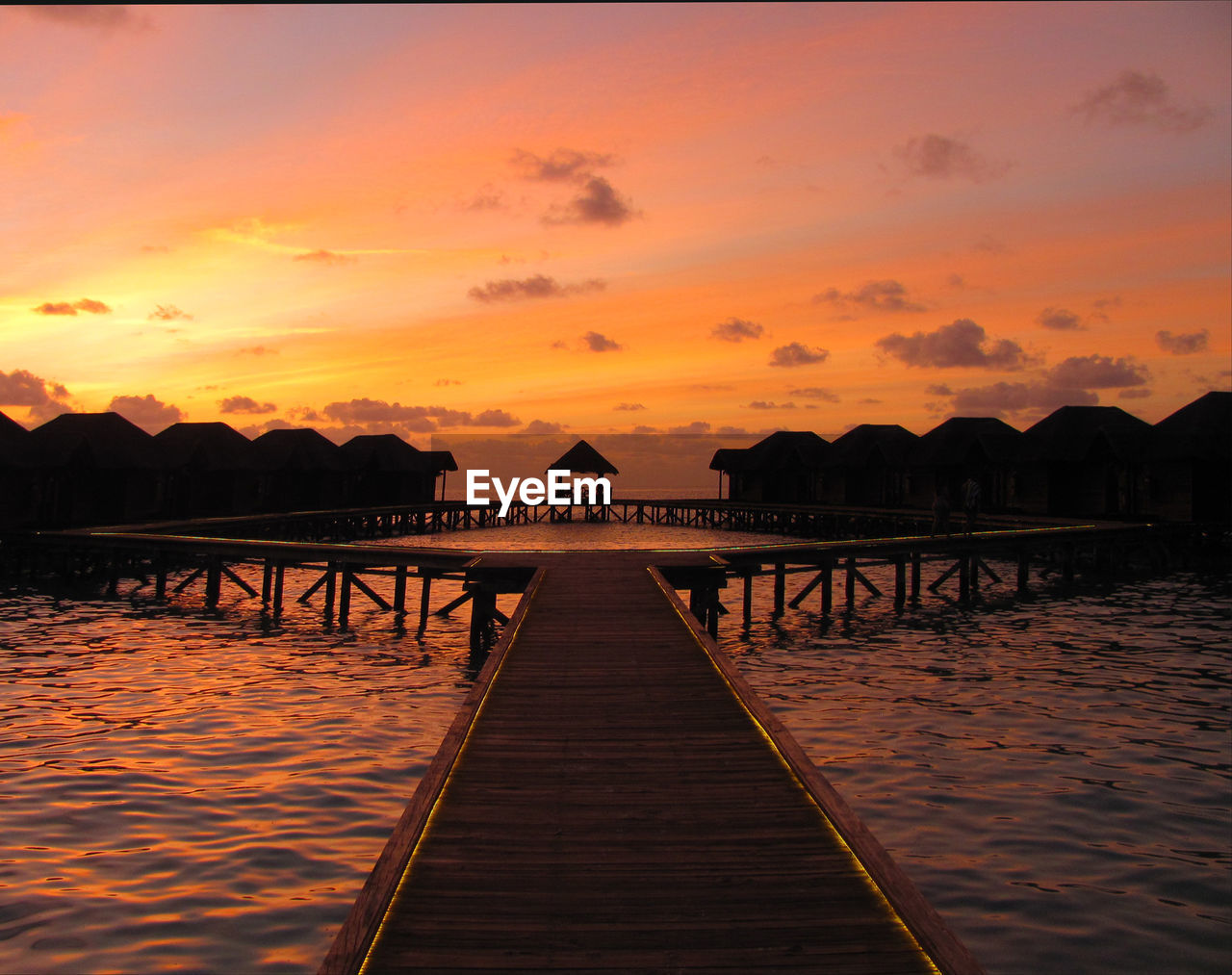 PIER OVER LAKE AGAINST ROMANTIC SKY