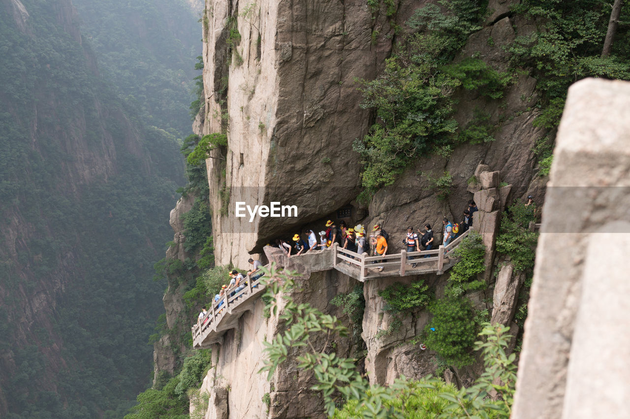Tourists on steps at huangshan mountain cliff
