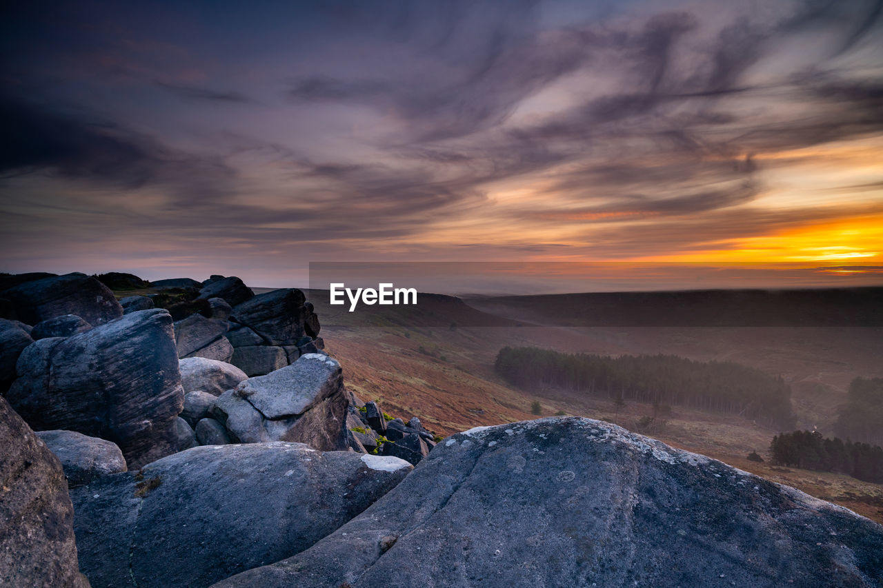 Rocks on land against sky during sunset