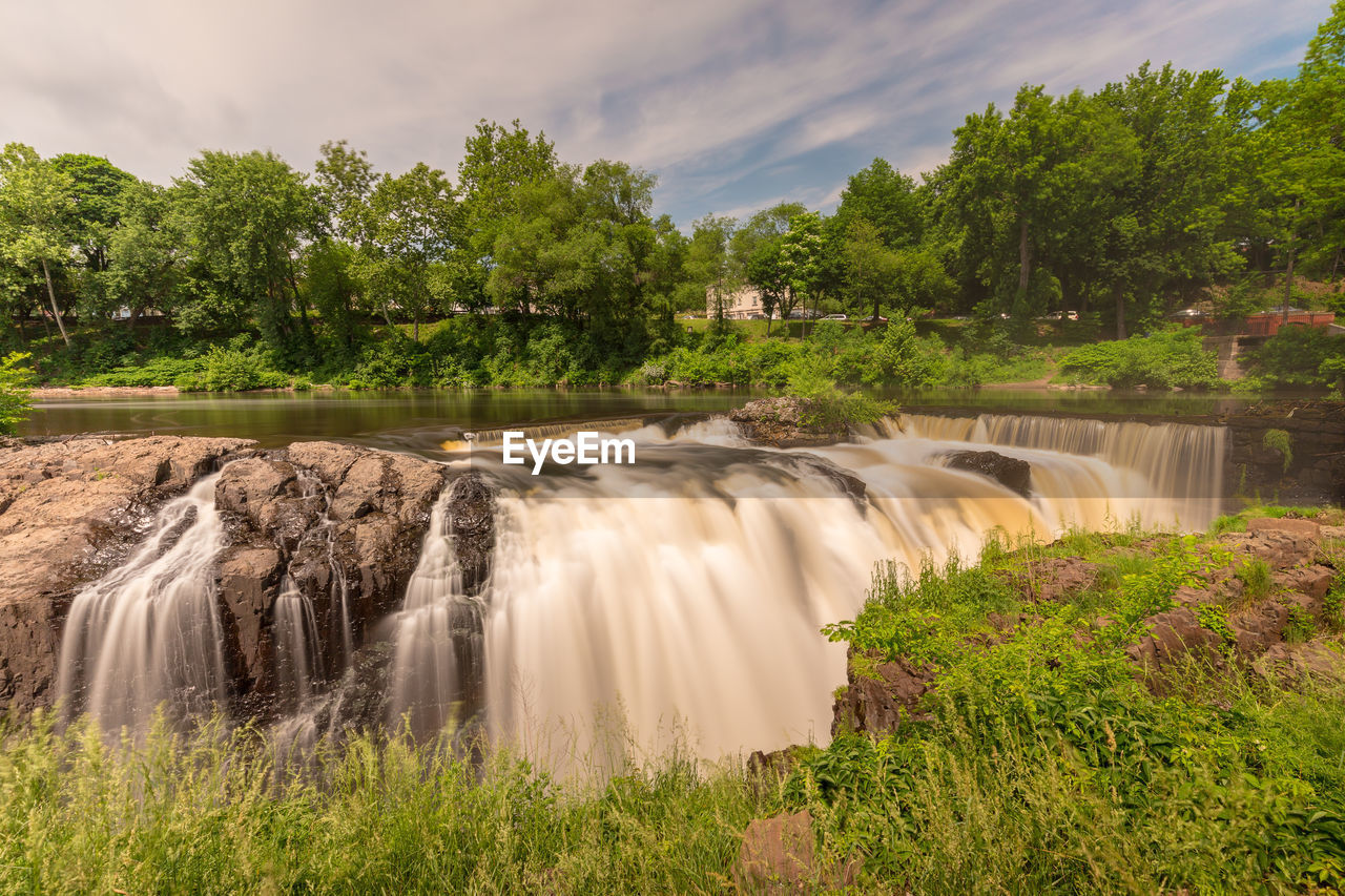 SCENIC VIEW OF WATERFALL AGAINST TREES AGAINST SKY