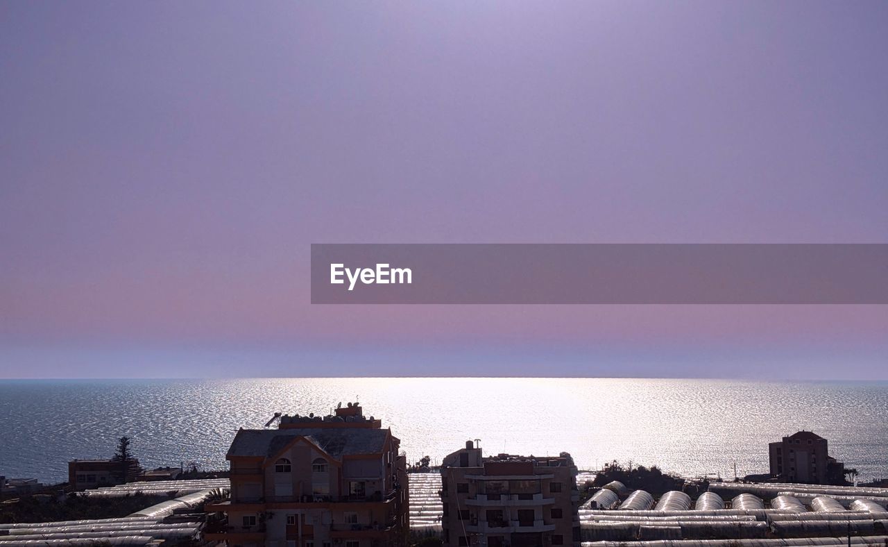 SCENIC VIEW OF SEA AGAINST BUILDINGS AGAINST CLEAR SKY