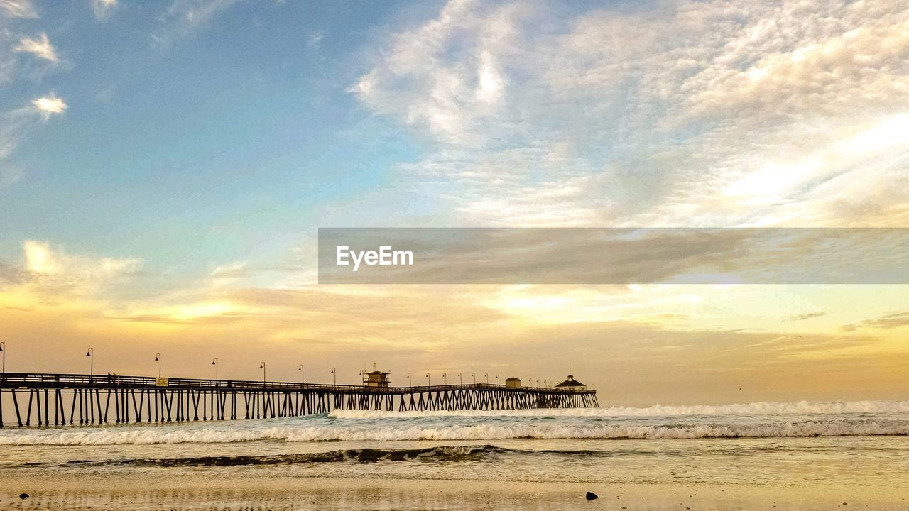 Pier over sea against sky during sunset