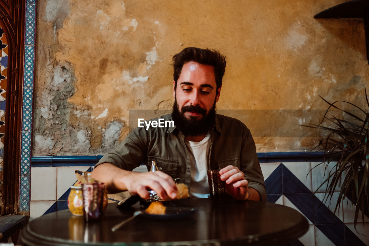 Man eating food while sitting on table in restaurant