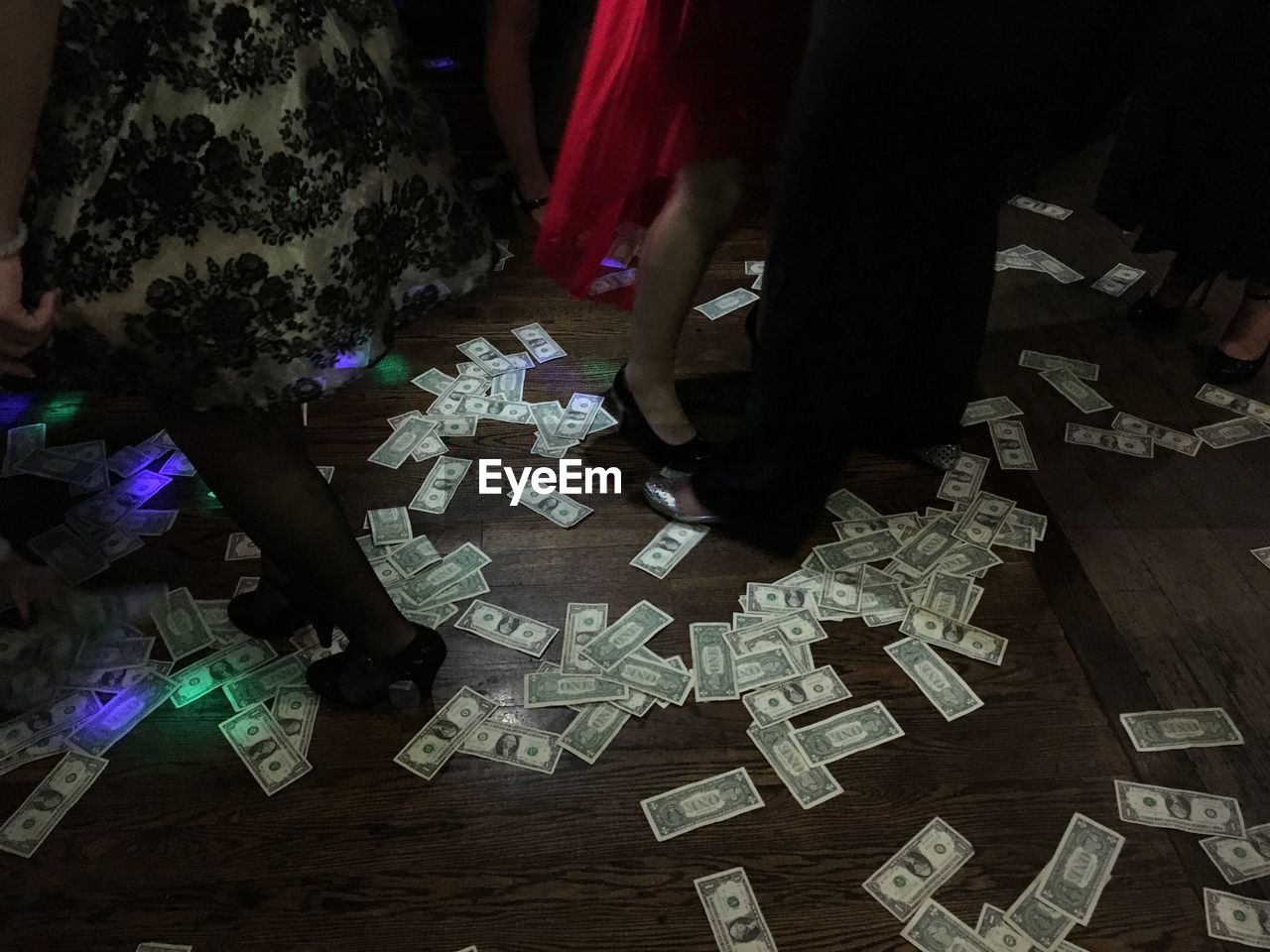 Low section of man and women dancing by paper currencies on stage