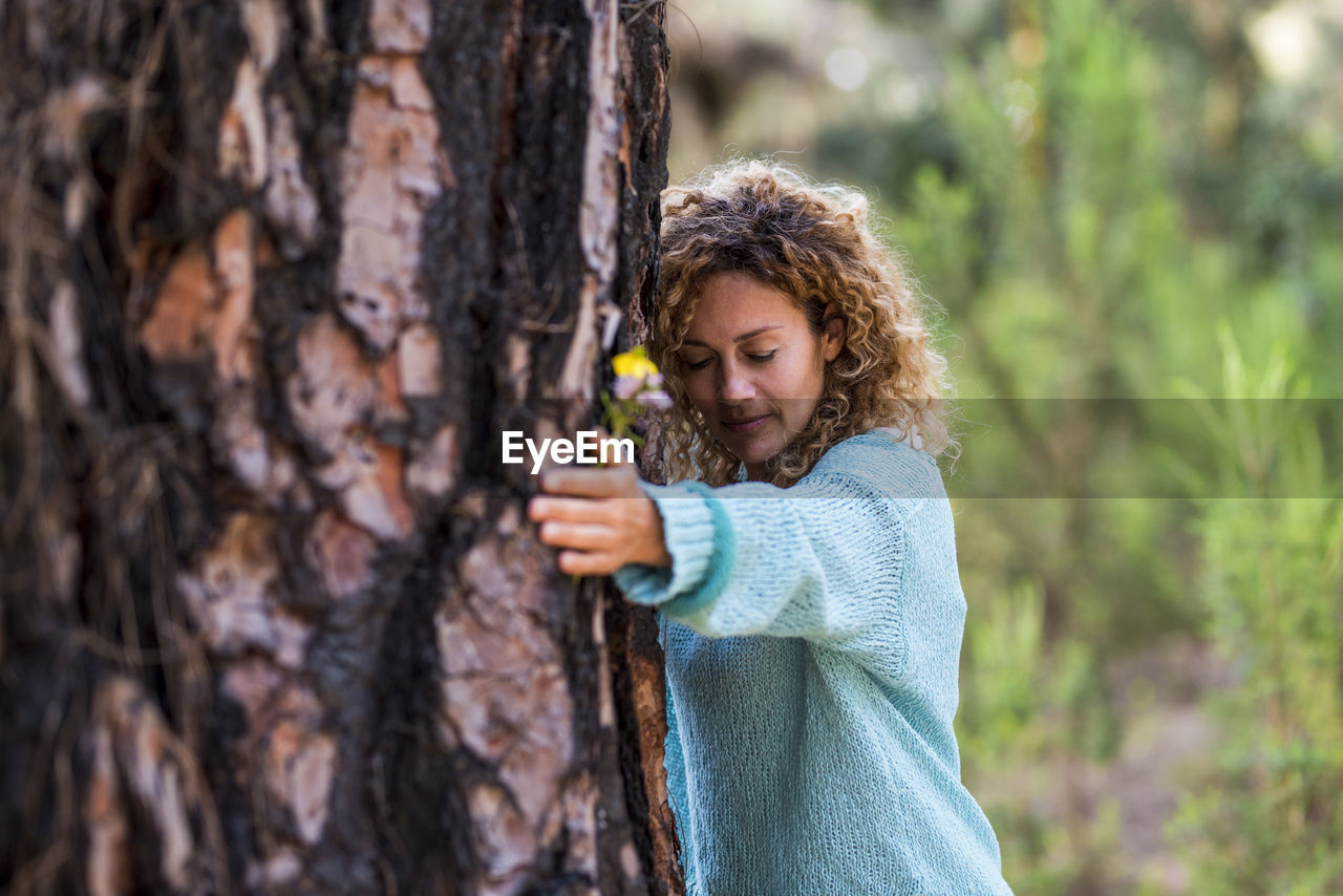 Girl holding tree trunk in forest