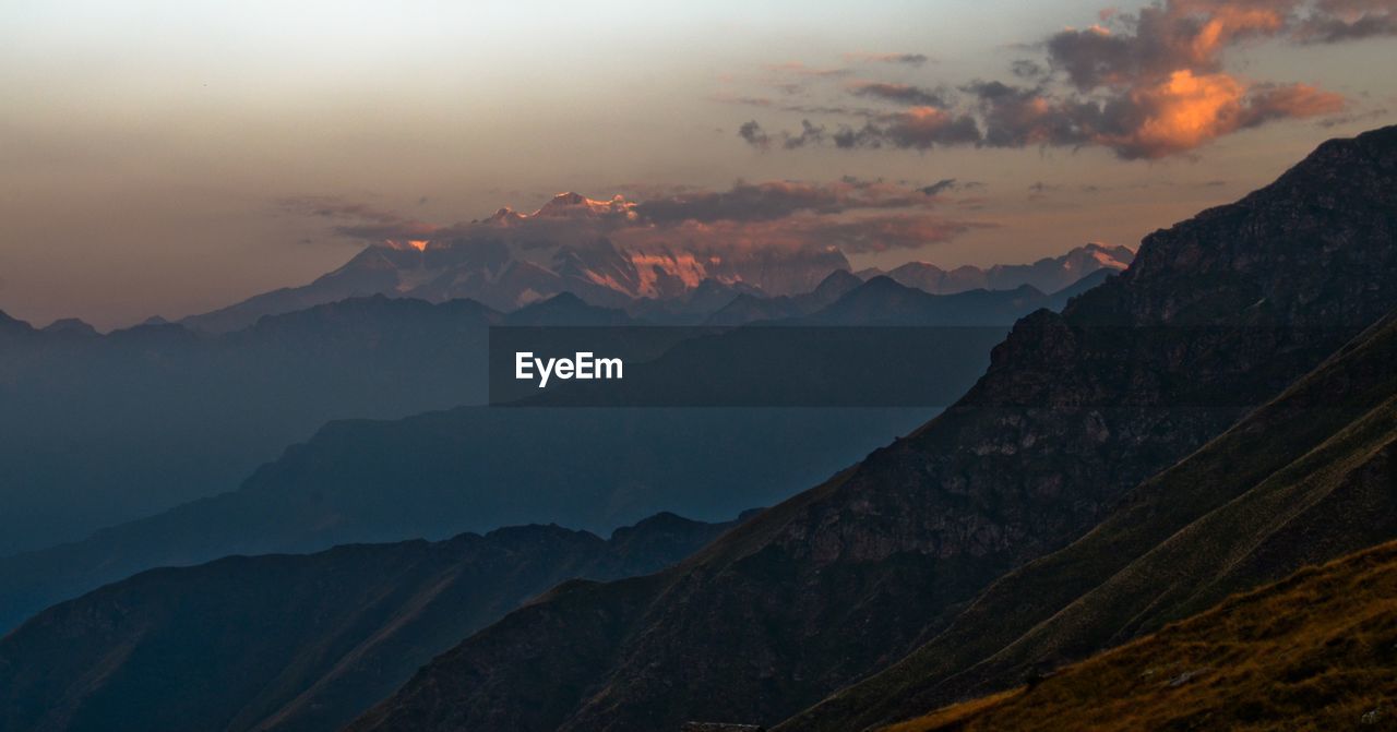 SCENIC VIEW OF MOUNTAINS AGAINST DRAMATIC SKY AT DUSK