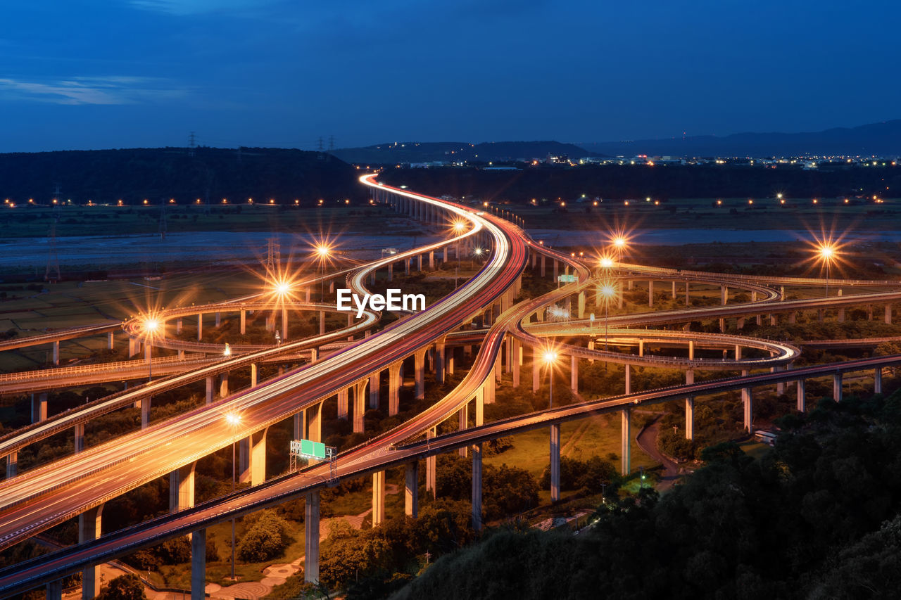 High angle view of light trails on bridges in city against sky at night