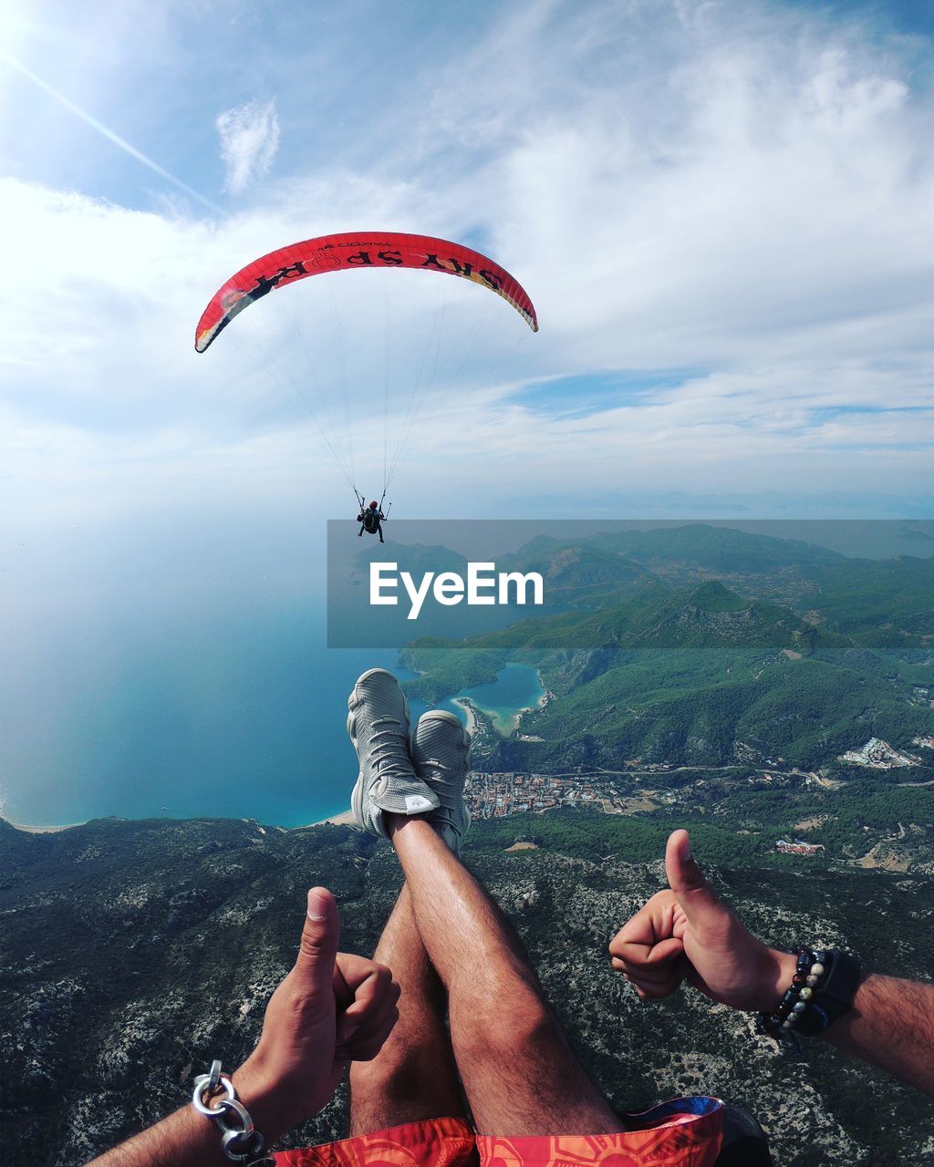 PEOPLE PARAGLIDING AGAINST SKY