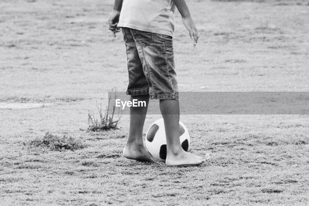 Low section of boy with soccer ball standing on field