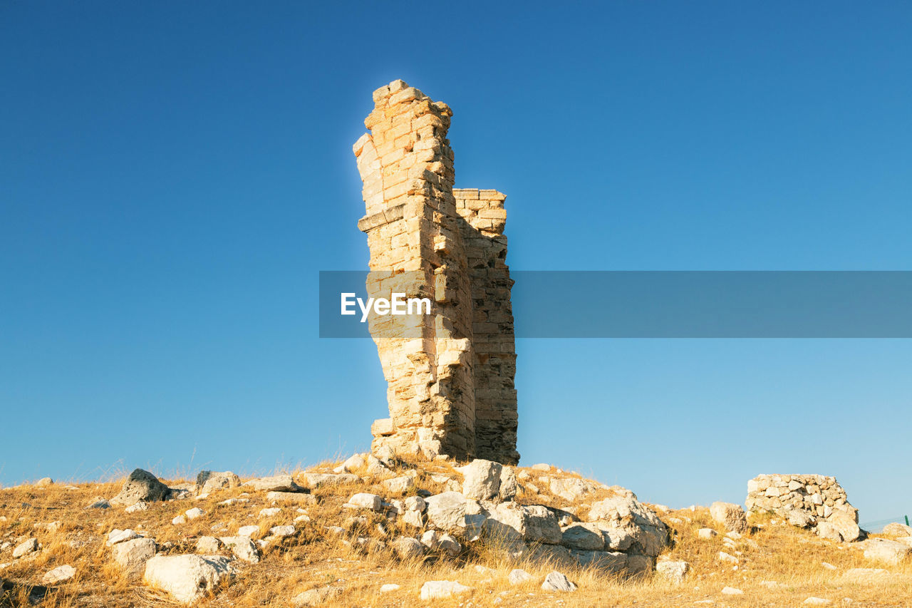 Low angle view of rock formation against clear blue sky