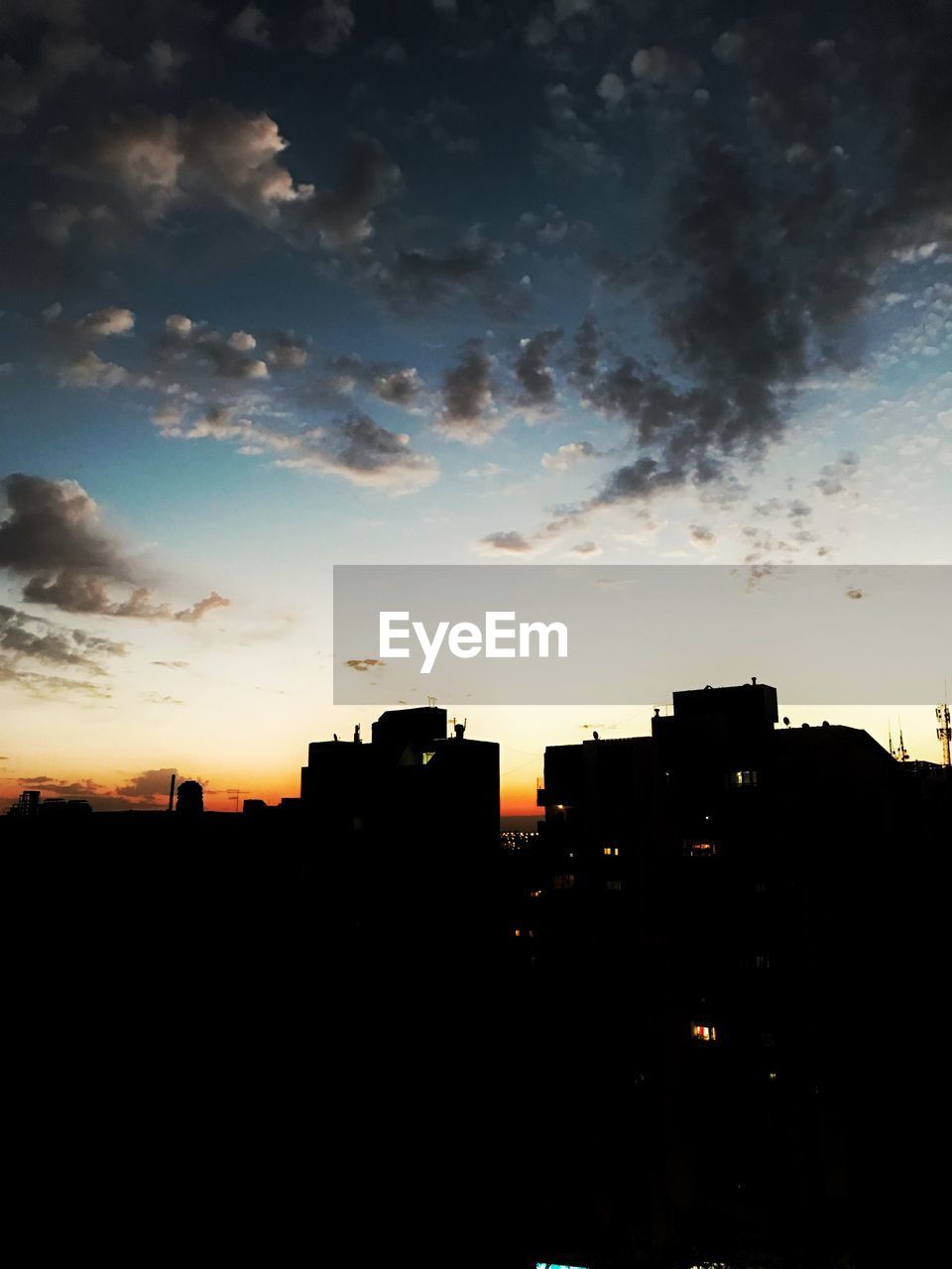 SILHOUETTE BUILDINGS IN CITY AGAINST DRAMATIC SKY