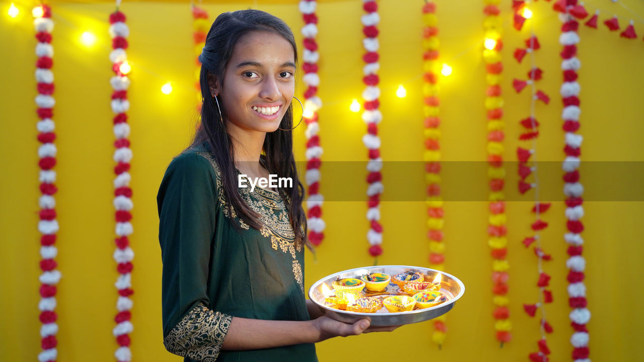 Diwali hindu festival of lights celebration. diya or oil lamp in woman hands with yellow background.